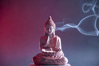 Statue of illuminated buddha against blue sky