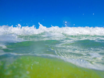 Close-up of sea waves splashing on shore against clear blue sky