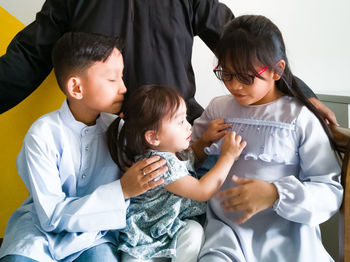 Siblings sitting on bench at home during eid-ul-fitr