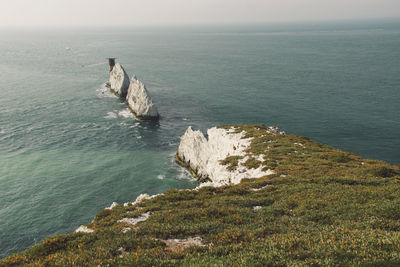 Scenic view of grassy cliff by sea