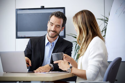 Young woman using phone while sitting in office