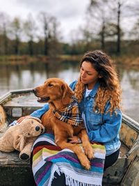 Woman with dog sitting by water