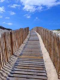 View of wooden boardwalk against sky and ocean