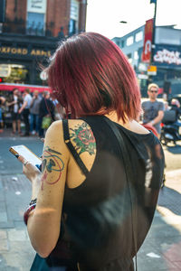 Rear view of woman using phone on street