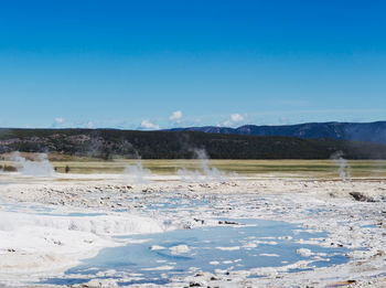 Scenic view of hot springs at yellowstone national park against cloudy sky