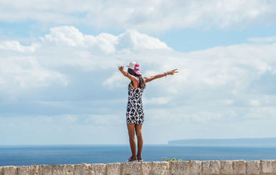 Full length of woman standing by sea against sky