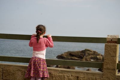 Rear view of woman standing by sea against sky