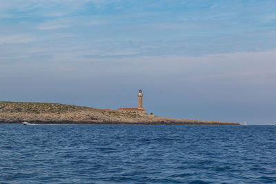 Lighthouse by sea against sky