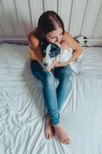 Young woman with dog on bed at home