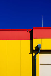 Low angle view of yellow building against clear blue sky on sunny day