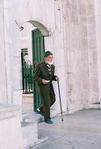 Full length of man holding umbrella standing against wall