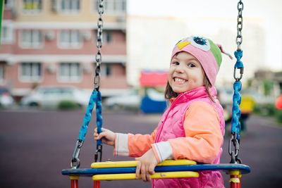 Portrait of smiling girl on swing in playground