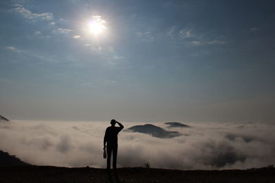 Silhouette of man standing on mountain road against sky