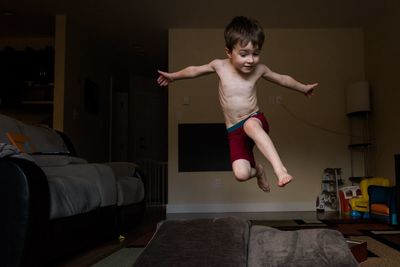 Full length of shirtless boy jumping