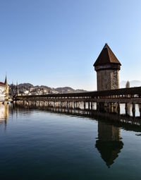 Bridge over river by building against clear sky