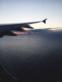 Cropped image of airplane flying over sea against the sky