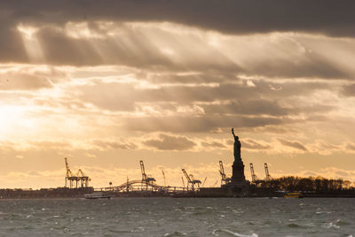 Silhouette of statue of liberty against cloudy sky during sunset