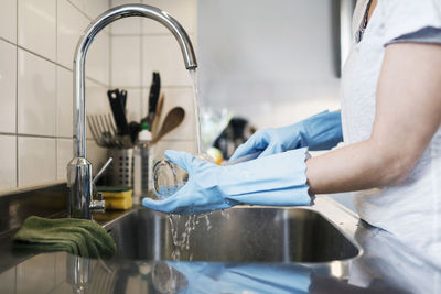 Midsection of woman washing glass at sink