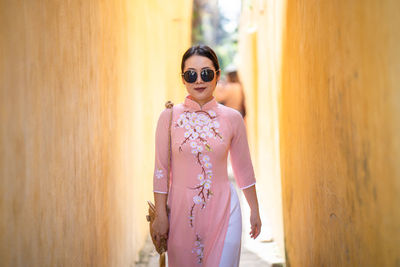 Woman with vietnam culture traditional dress walking between yellow building in hoi an.
