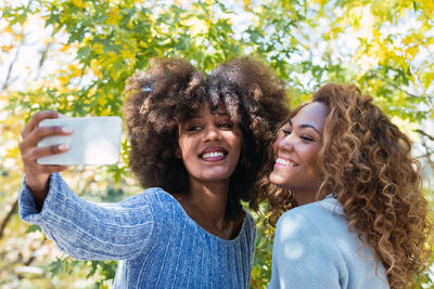 Cheerful female friends doings selfie outdoors