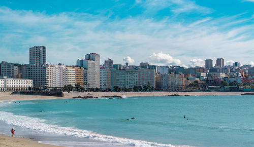 Sea by city against sky