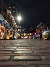 Illuminated city street against sky at night