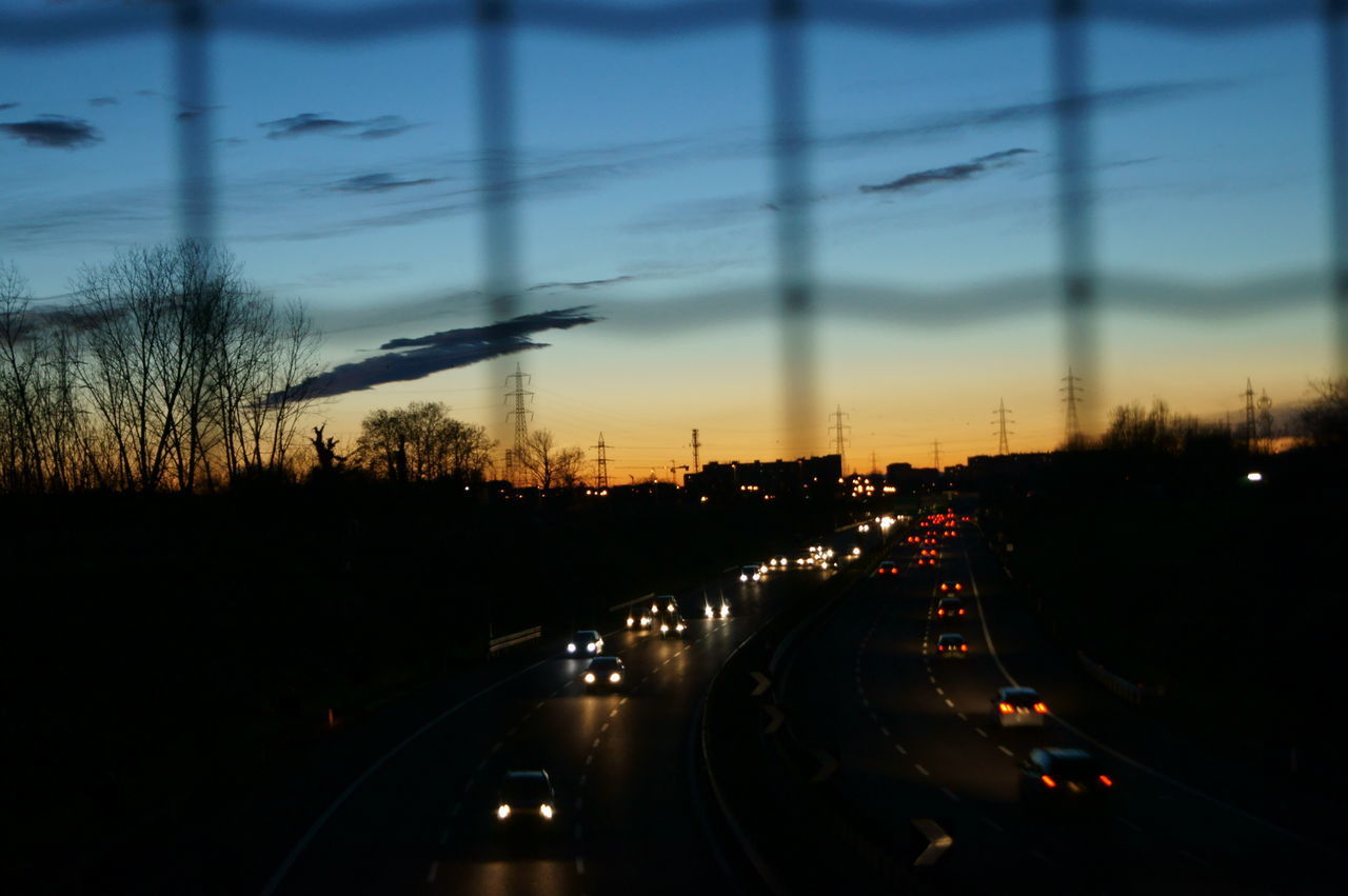 CLOSE-UP OF CARS MOVING ON ROAD AGAINST SKY