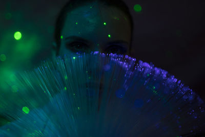 Portrait of beautiful young woman against illuminated background