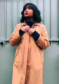 Portrait of woman standing against wall