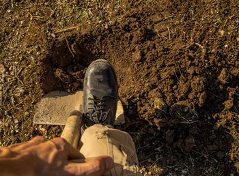 Low section of man digging hole with shovel on field