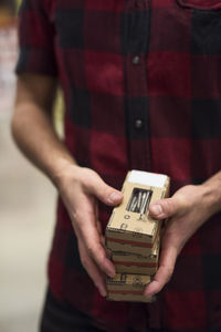 Midsection of male customer holding screw boxes in store