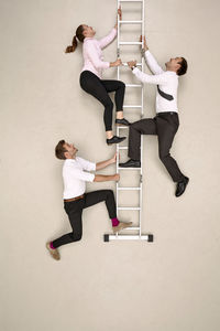 Three business colleagues climbing ladder