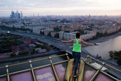 Rear view of woman standing by railing against buildings