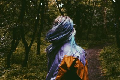 Woman tossing dyed hair in forest