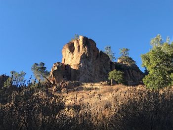 Low angle view of rock formation against clear blue sky