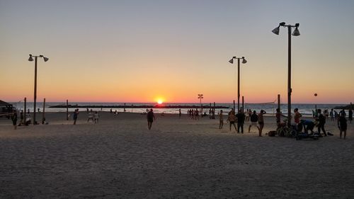 People on beach against sky during sunset