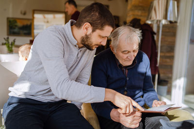 Son with father reading book while sitting at home