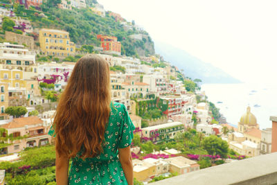 Rear view of woman standing by buildings in city