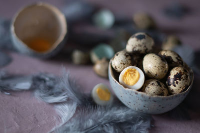 Quail eggs in ceramic vases, gray feathers on the table, easter still life,