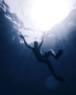 Low angle view of silhouette man swimming in sea