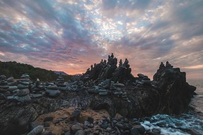 Rocks in sea against sky during sunset