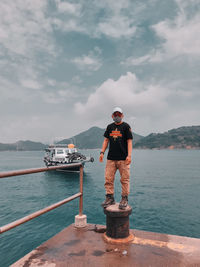 Man standing on boat in sea against sky