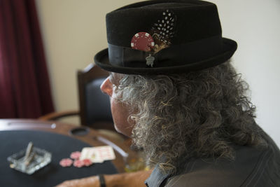 Close-up of man wearing hat with gambling chip and feather