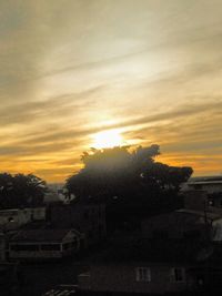 Silhouette trees and buildings against sky during sunset