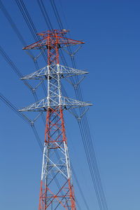 Low angle view of electricity pylon against clear blue sky