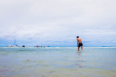 Rear view of man standing on beach against sky