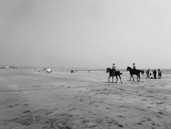 People on beach against clear sky