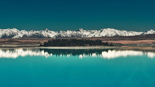 Scenic view of lake and mountains against clear blue sky