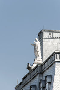 Low angle view of statue against building against clear sky