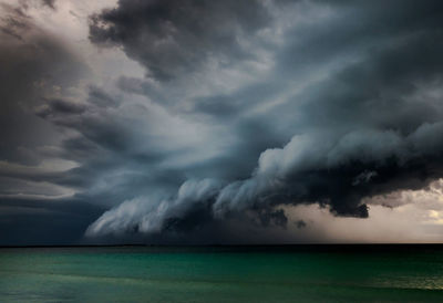 Scenic view of thunderstorm over sea against cloudy sky